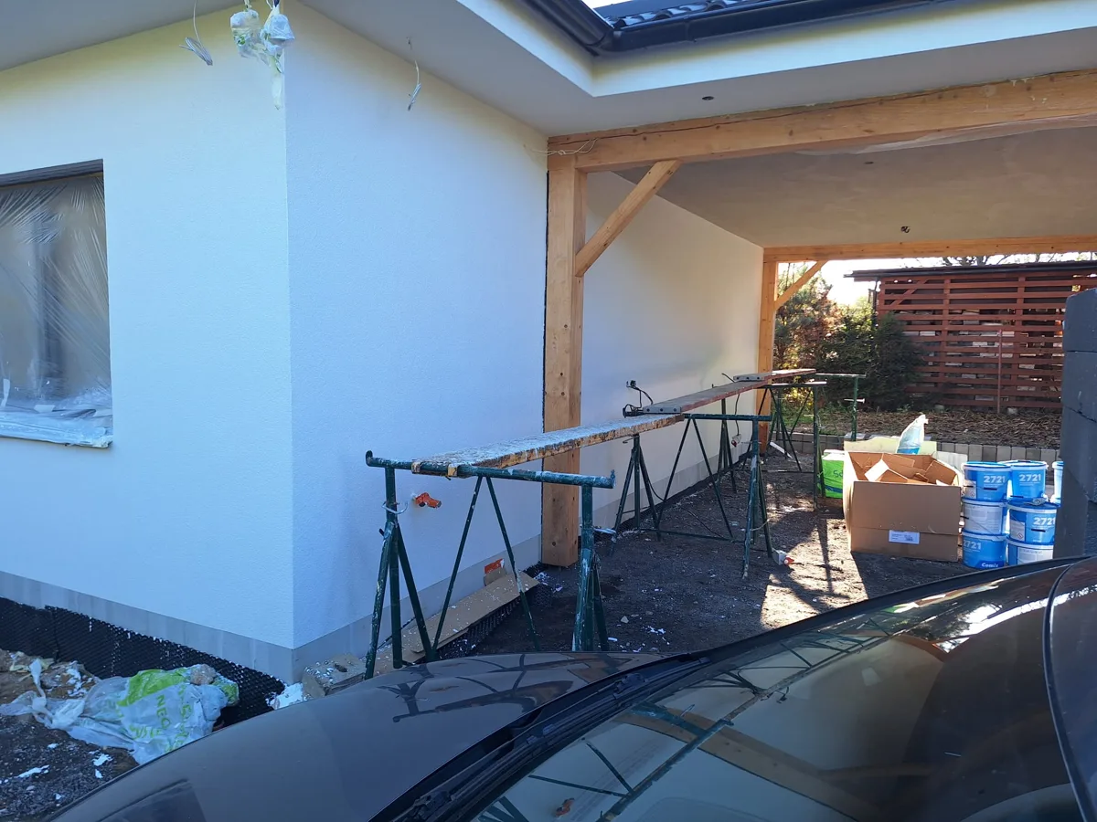 Dokončený bílý bungalov s dřevěným přístřeškem